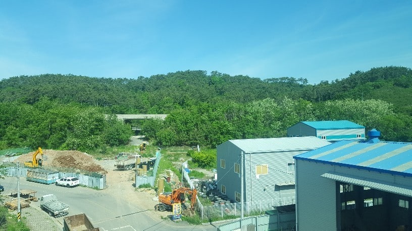 手前に工場と奥に森の風景。