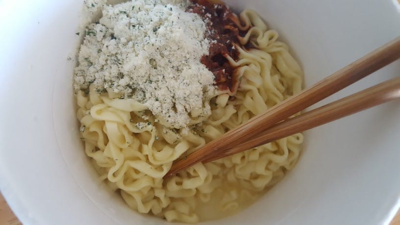 麺に液体ソースと粉末スープをかけた写真